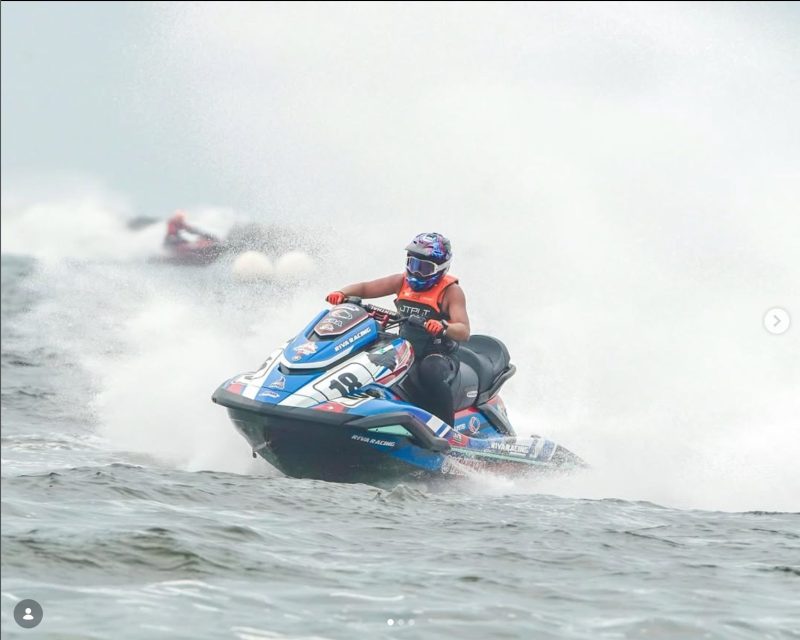 Waverunner racer Makayo Makaio Wimylie speeding through the waves on a blue Riva Racing jet ski number 18.